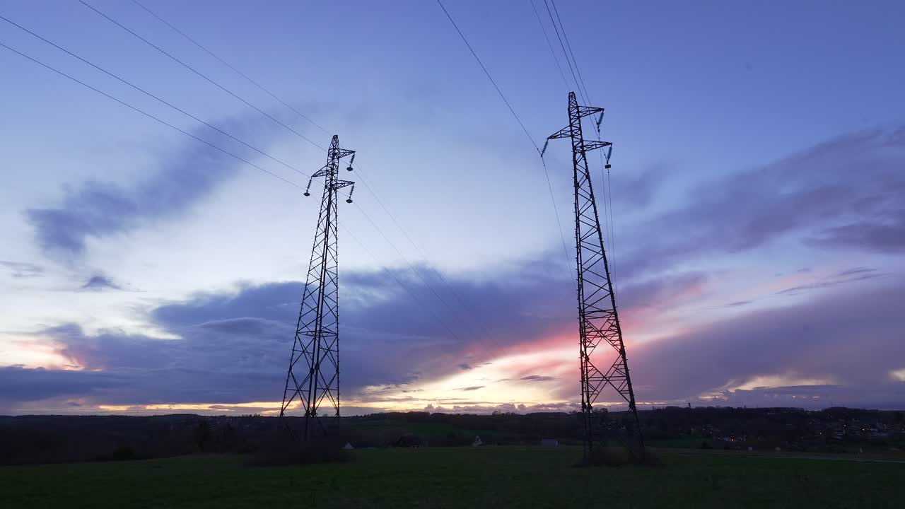 Cinematic blue hour sky time lapse of clouds and sunset glow behind utility towers