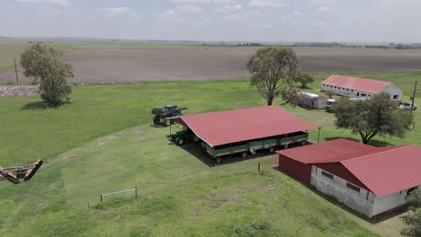 aerial 4k footage of a farm house with farming equipment, a high speed sprayer for crops, driving around the farm