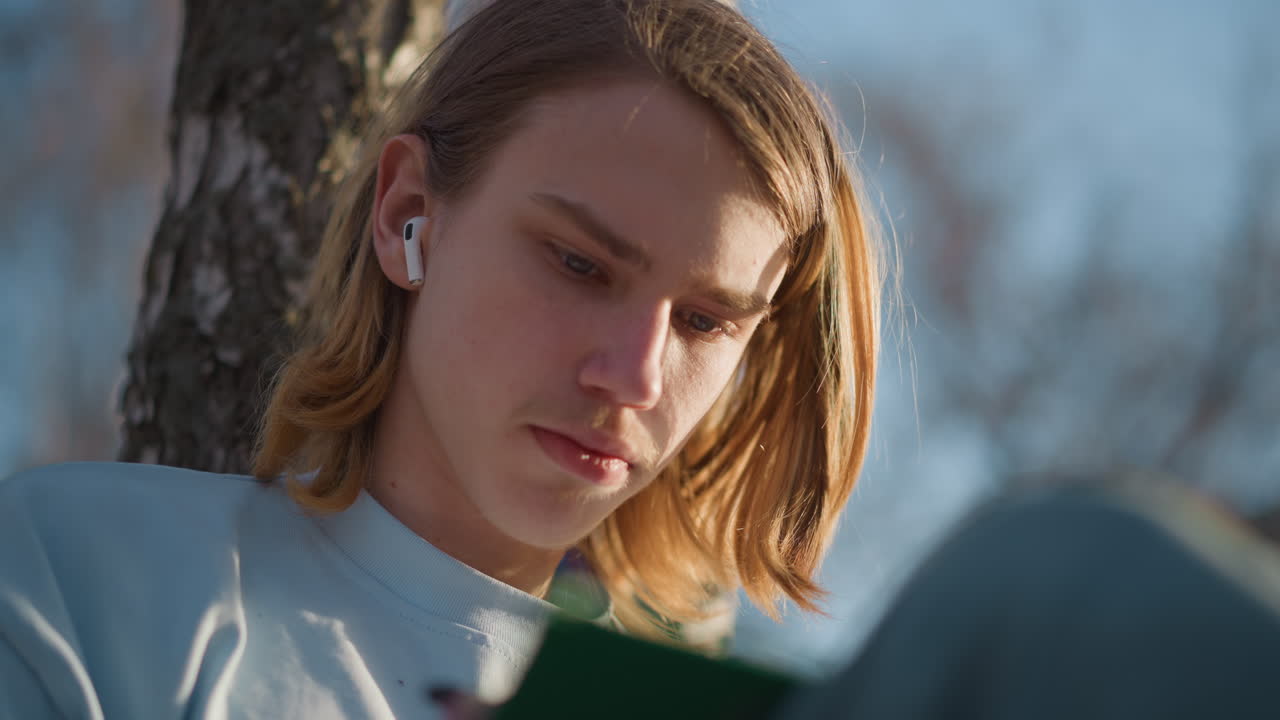 야외에서 책을 읽는 어린 독자들, 야외 독서에 몰두한 청소년, 화창한 하늘 아래에서 공부하는 어린 학생, 낮 시간에 공원에서 평화롭게 독서하는 십 대들