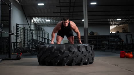 man performing a tire flip exercise in a gym