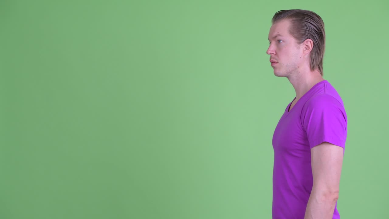 vista de perfil de un joven sonriendo contra un fondo verde