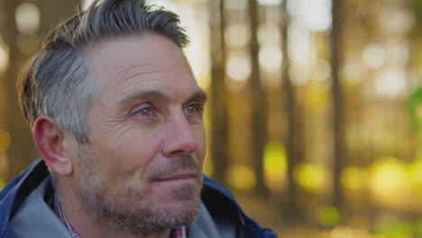 head and shoulders shot of mature man on relaxing walk through fall or winter countryside breathes in deeply - shot in slow motion