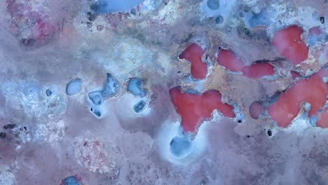 aerial birds eye: icelandic red colored boiling mud pools in volcanic crater landscape of iceland - phenomenal aerial of natural sulfuric steam rising up into air