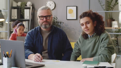 portrait of senior male mentor and young trainee in office