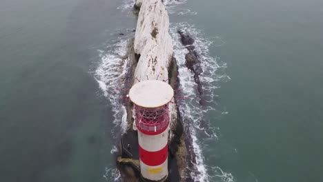 Vuelo-De-Drones-Aéreos-De-4k-30fps-Que-Pasa-Sobre-El-Faro-Rojo-Y-Blanco-Para-Revelar-Lentamente-Los-Acantilados-Blancos-De-Las-Agujas-En-La-Costa-De-La-Isla-De-Wight