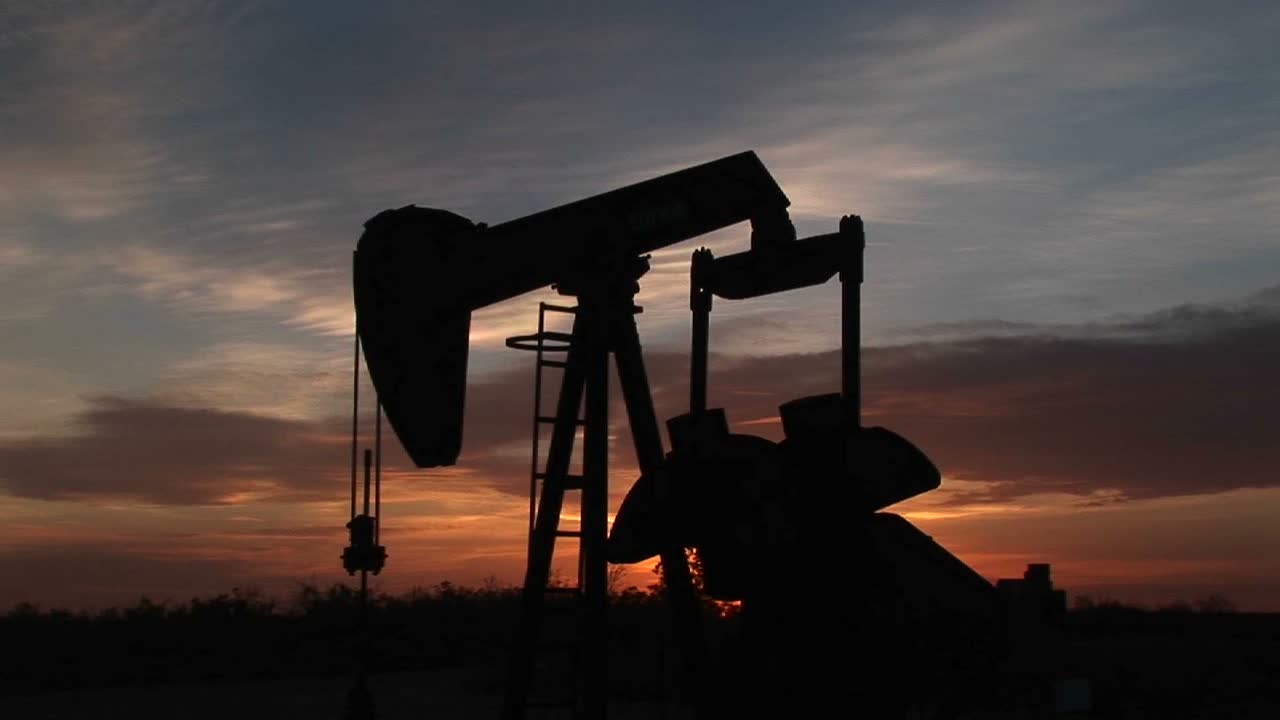 una plataforma petrolera bombea gas contra una puesta de sol