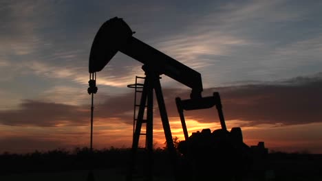 an oil rig pumps gas against a sunset