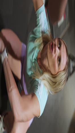 vertical shot of blond personal trainer teaching her client how to squat, close up