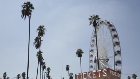 empty ferris wheel spins, classic vintage tickets counter, palm trees, slow motion low angle