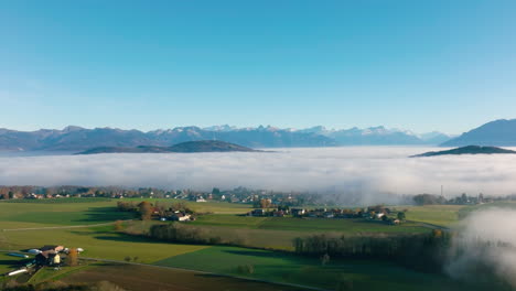 savigny village appearing from winter fog covering the geneva lake region with the alps in the background in vaud, switzerland