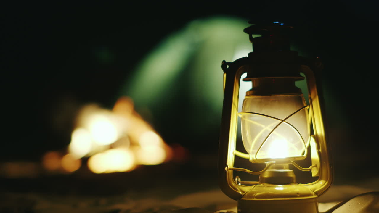 lámpara de queroseno se encuentra en la arena en el fondo una carpa de fuego