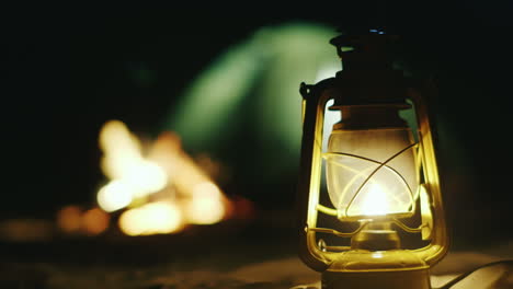 kerosene lamp stands on the sand in the background a fire tent