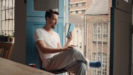 happy man at home in pajamas calling friends using digital tablet app