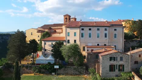 Old-town-on-top-of-a-hill-surrounded-by-woods,-perspective-drone