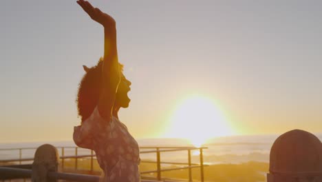 Woman-standing-with-her-arms-wide-open-at-sunset