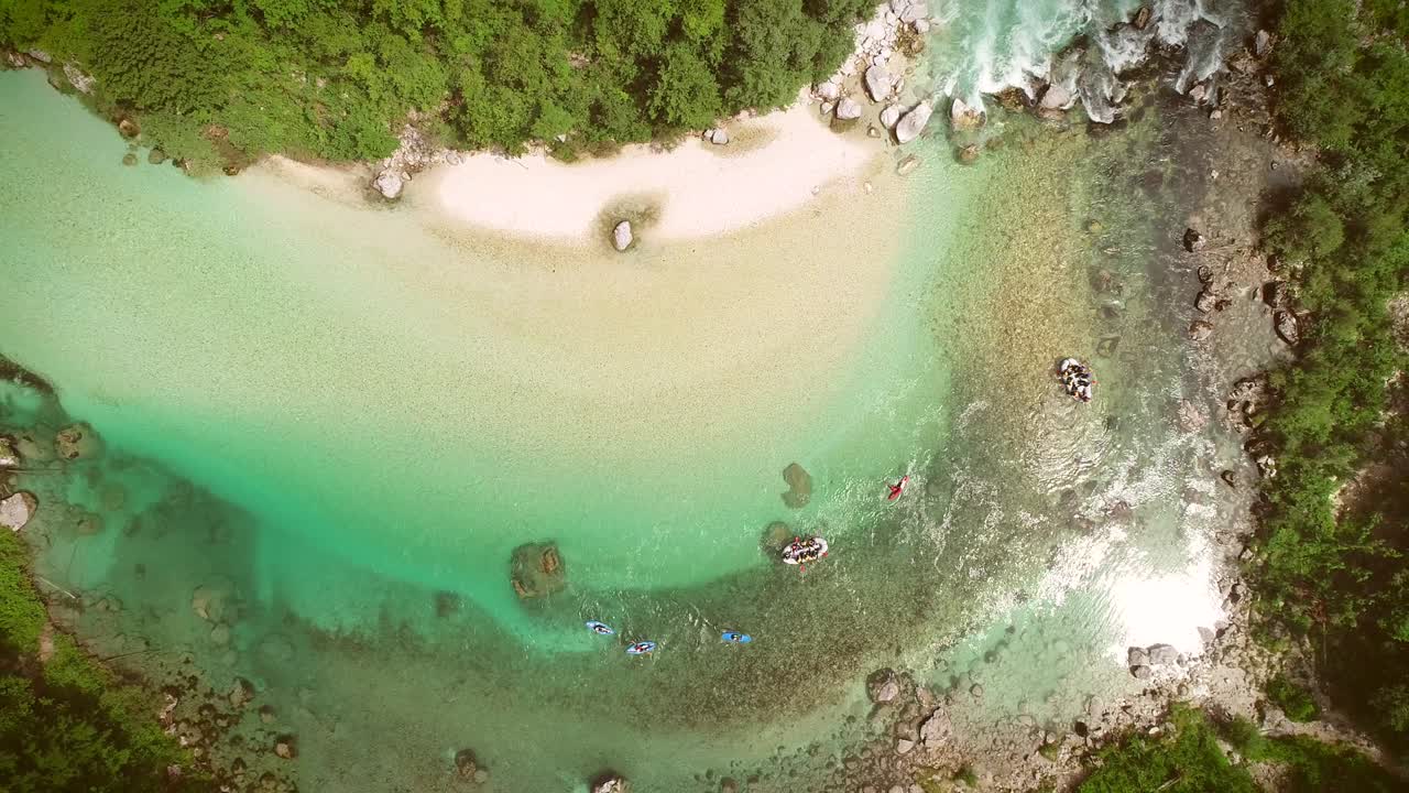 슬로베니아 의 소카 강 에 있는 바위 들 에 둘러싸여 라프팅 을 하는 사람 들 의 공중 사진.