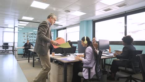 male boss giving documents to female office workers