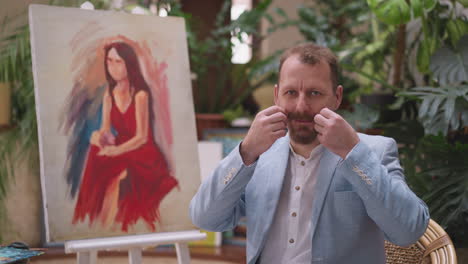 artist posing with his portrait painting