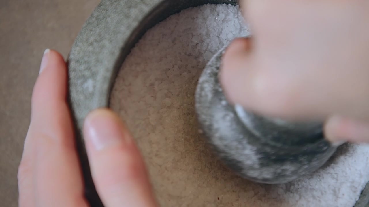 Nærbillede af en morterstøder, der knuser salt.