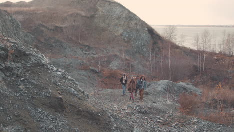 group of teenage friends are talking and walking in a mountain path on a windy day 1