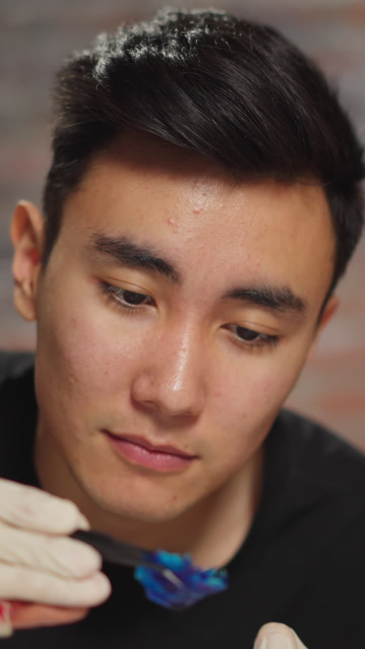 Asian chemistry teacher shows colored litmus test to smiling little girl with protective goggles during fun science lesson in lab closeup