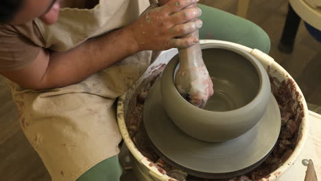 Looking-down-over-craftsman-doing-finishing-touch-to-beautiful-grey-flowerpot-on-workshop-turntable