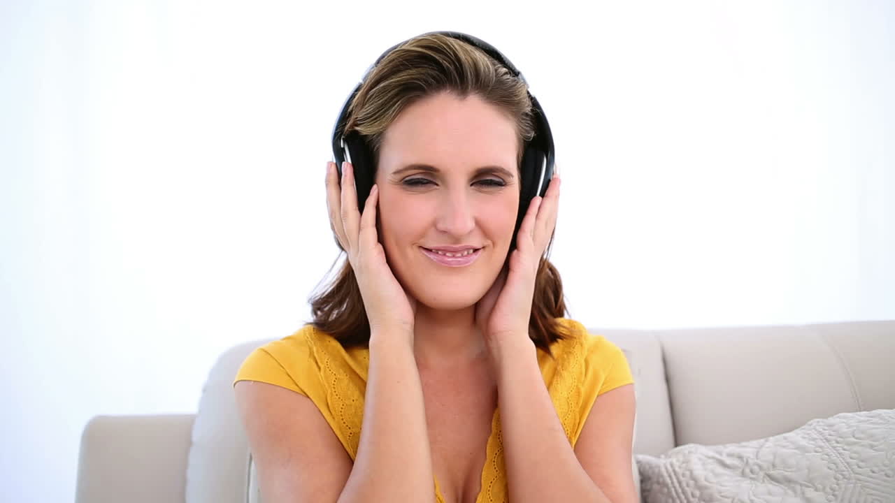 mujer sonriente escuchando música en el sofá