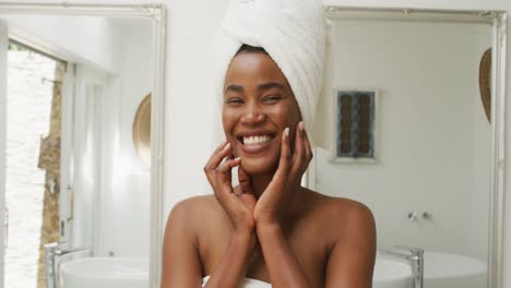 video of happy african american woman in robe smiling at camera