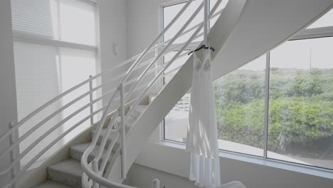 An-elegant-wedding-dress-hangs-in-natural-light