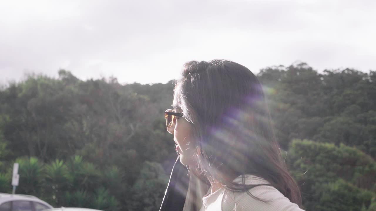 그레이트 오션로드, 빅토리아, 호주를 따라 눈부신 태양 광선 아래 재킷을 입고 선글라스에 여성