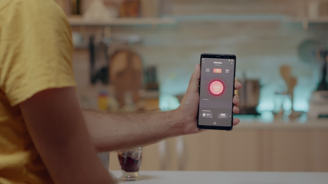 Man holding smartphone with lighting control application, turning on the lights