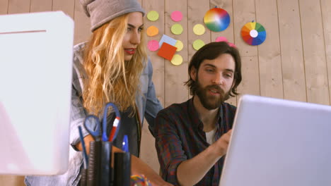 diseñadores casuales sonrientes trabajando en una computadora portátil
