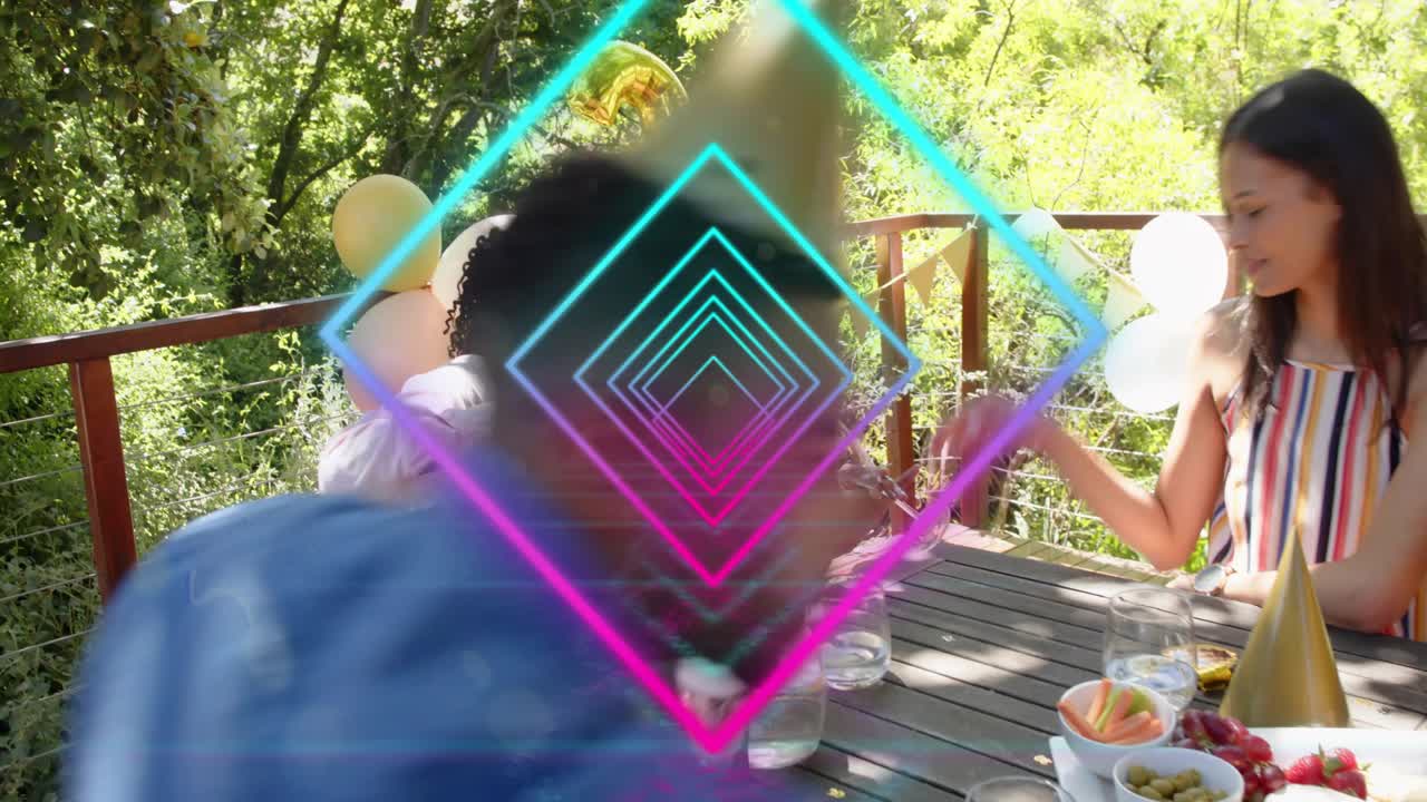 Man reaching, handing gift bag to birthday recipient on deck, neon diamond overlay obscuring group