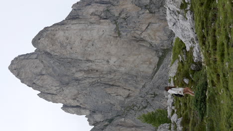 vertical carefree woman hiking under dolomites mountain peak in ra gusela, italy