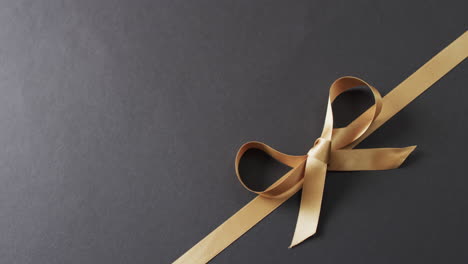 Video-of-gold-gift-ribbon-and-bow-with-copy-space-on-black-background