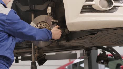 car mechanic replacing car wheel brake shoes of lifted automobile at repair service station