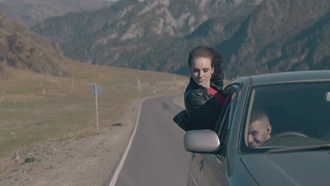 brunette leans out of car window and takes off black jacket