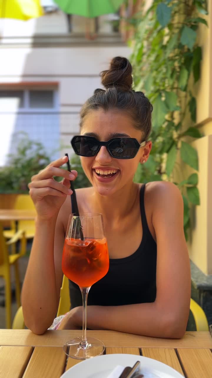 Adolescente che sorseggia un Aperol Spritz in un caffè all'aperto