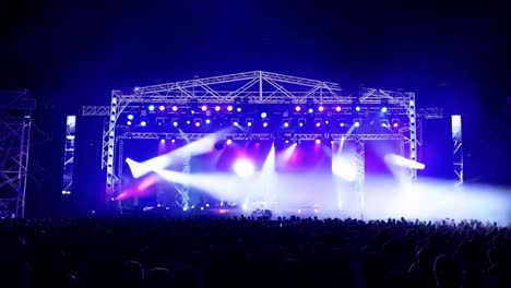 una gran multitud de personas viendo un concierto en el escenario con luces brillantes.