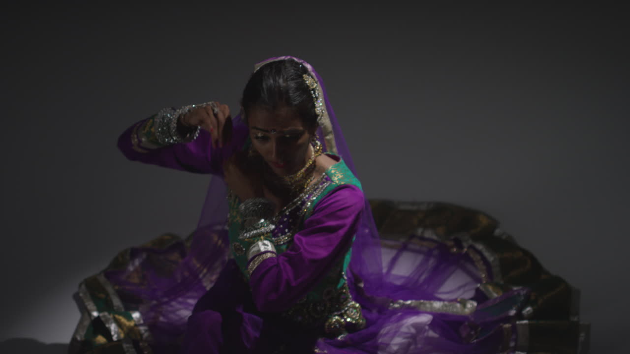 bailarina de kathak femenina realizando un baile vestida con el vestido tradicional indio sentada en el suelo en el centro de atención 5