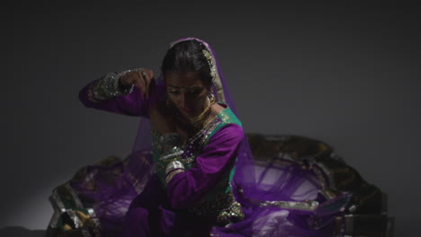 bailarina de kathak femenina realizando un baile vestida con el vestido tradicional indio sentada en el suelo en el centro de atención 5