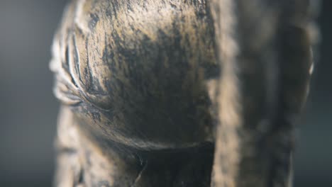 A-close-up-macro-detailed-slow-tilt-up-shot-from-behind-of-a-spartan-face-design,-warrior-ancient-greek-bronze-helmet,-on-a-360-rotating-stand,-studio-lighting,-4K-smooth-movement