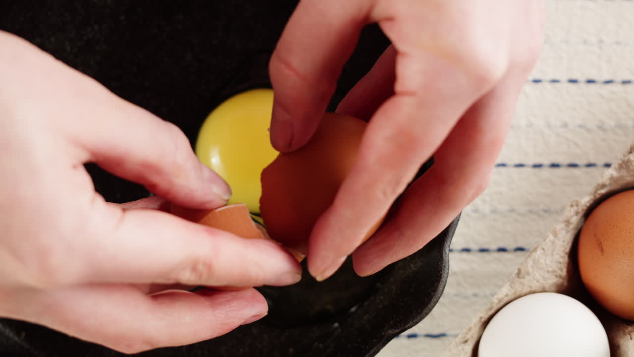 Close Up of Hand Cracking a Fresh Egg into a Frying Pan