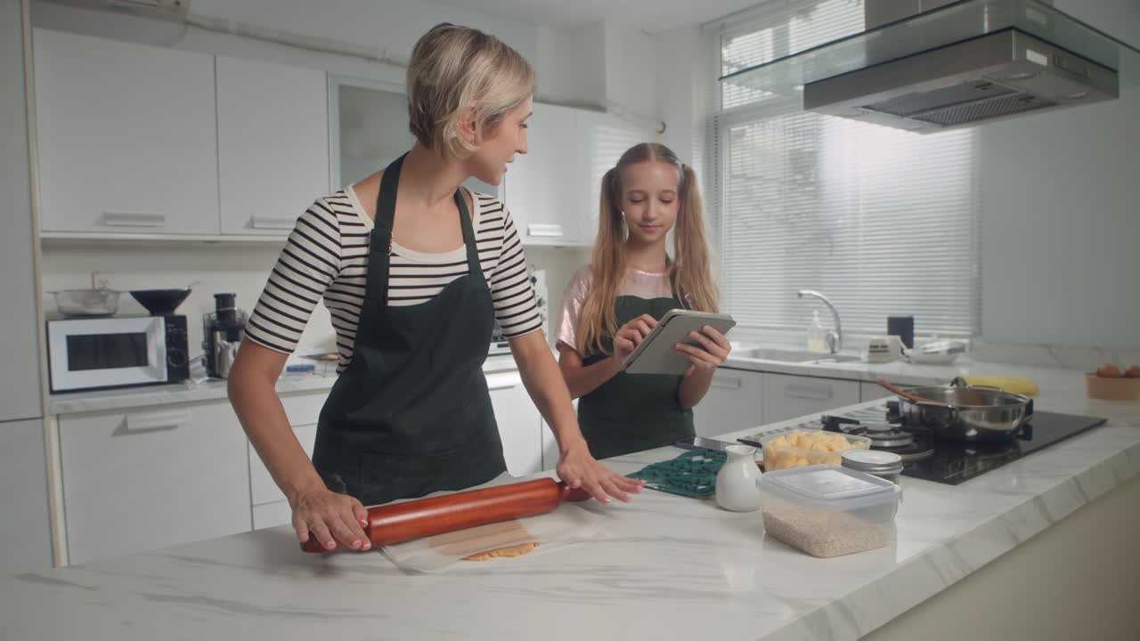 Daughter Guiding with Recipe Mother Rolling Dough for Cookies