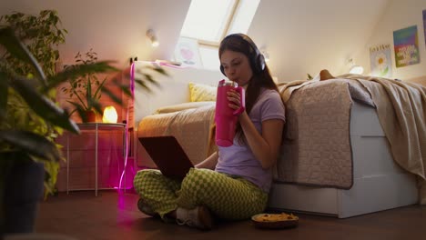 una adolescente relajándose en el dormitorio con una computadora portátil