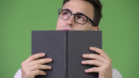 young handsome nerd man covering face with book