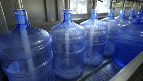 a detailed look at a water bottling production line, showing large water containers being filled with purified water