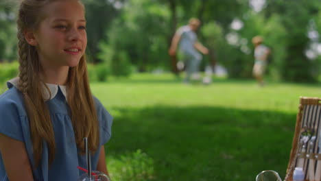 Calm-girl-watching-football-training-father-with-son-on-green-lawn-closeup.