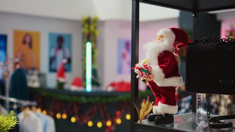 close up panning shot of miniature santa claus figure used as christmas decoration in empty fashion boutique during winter holiday season. xmas ornaments in clothing store