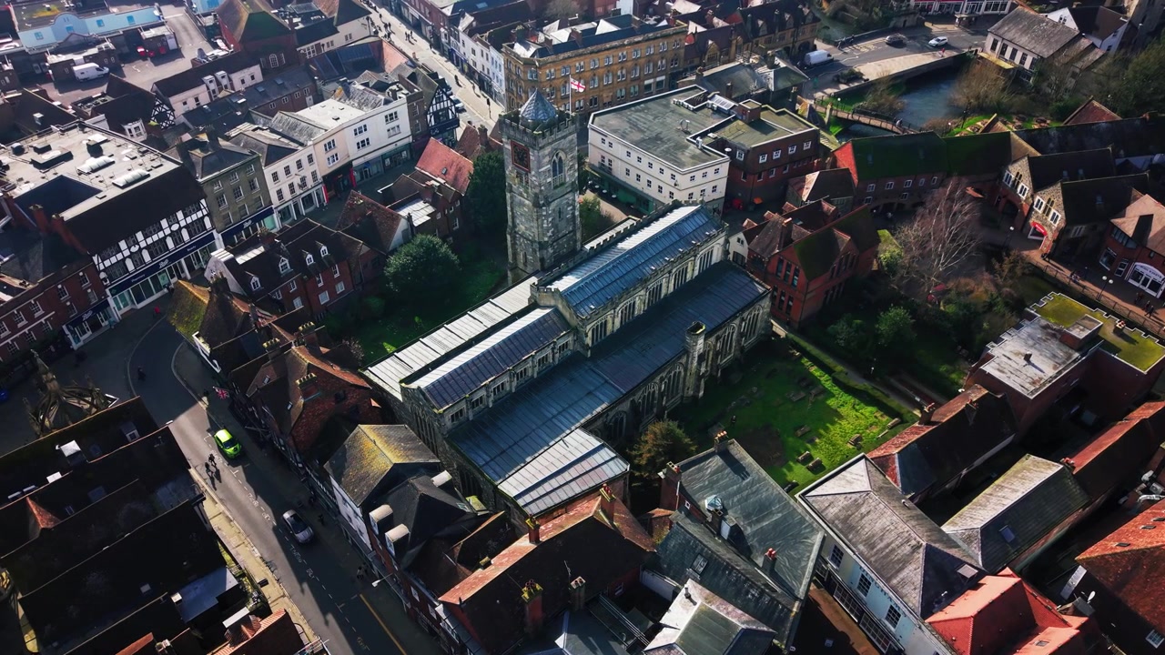 Høy droneutsikt som viser hele fotavtrykket av St Thomas Church omgitt av historiske bygninger og gater i sentrum av Salisbury, England